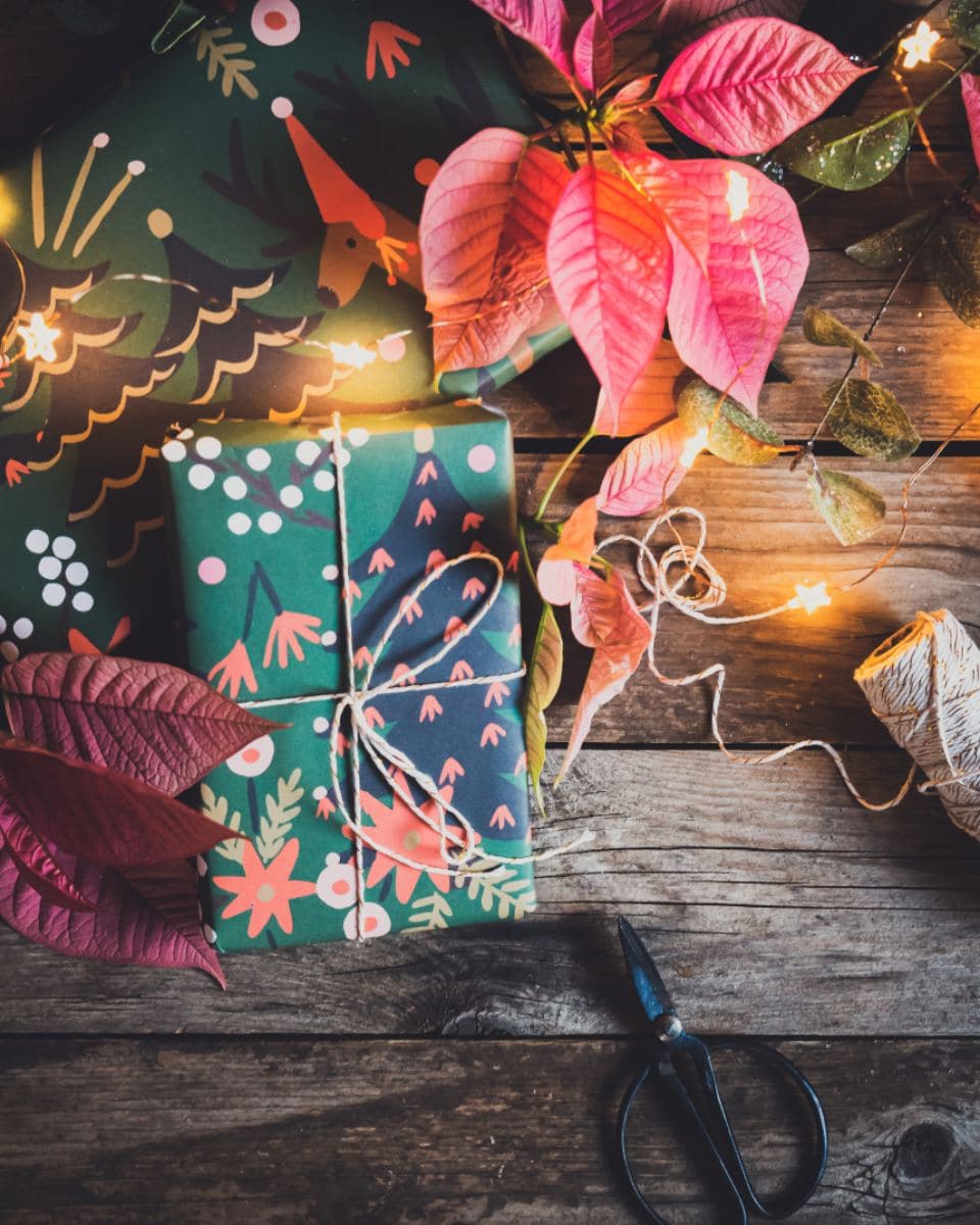 Christmas presents being wrapped on a wooden table